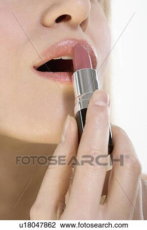 Stock Image - Closeup of lips with lipstick tube. Fotosearch
