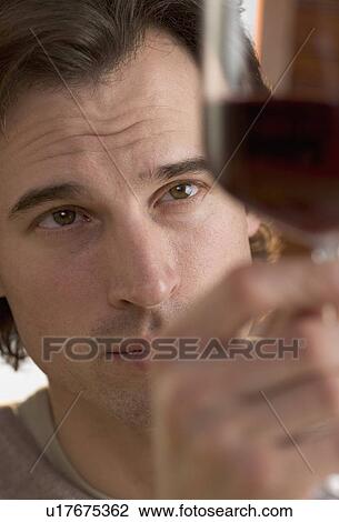 Stock Image - Closeup of man looking at wine. Fotosearch
