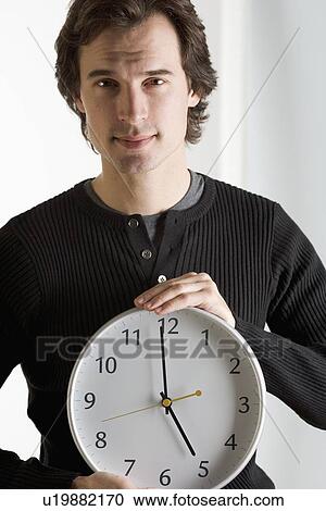 Stock Image - Closeup of man with clock. Fotosearch