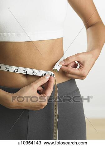 Closeup of woman measuring her waist View Large Photo Image Stock Image - Closeup of woman measuring her waist. Fotosearch
