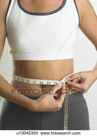 Stock Photography - Closeup of woman measuring her waist. Fotosearch