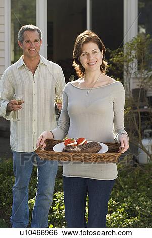 Stock Photograph - Couple carrying food and drink outdoors. Fotosearch