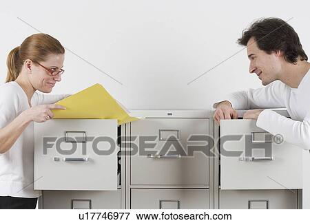 Stock Photo - Couple gazing lovingly over file cabinets. Fotosearch