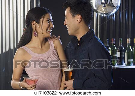 Stock Image - Couple having drinks in a bar. Fotosearch