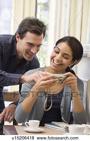 Couple looking at digital camera in restaurant View Large Photo Image Stock Photo - Couple looking at digital camera in restaurant. Fotosearch