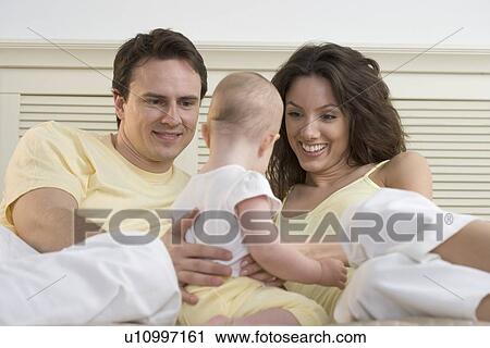 Couple relaxing with infant View Large Photo Image Stock Image - Couple relaxing with infant. Fotosearch