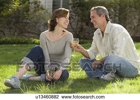 Couple sitting in grass drinking wine View Large Photo Image Stock Image - Couple sitting in grass drinking wine. Fotosearch