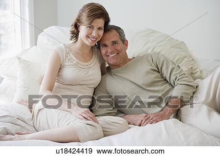 Stock Photo - Couple sitting on bed. Fotosearch