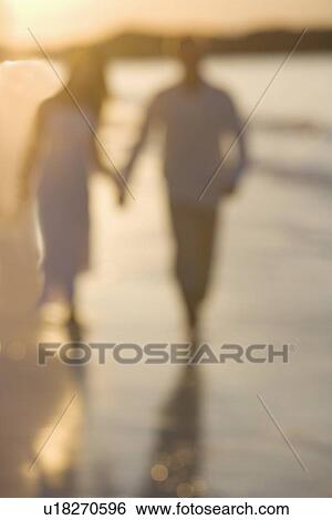 Stock Photograph - Couple strolling on a beach. Fotosearch