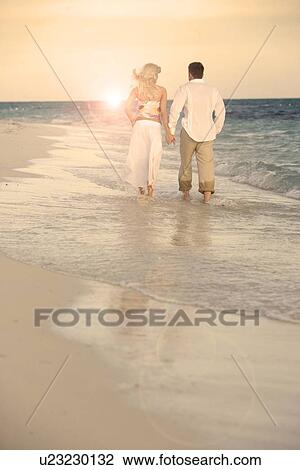 Stock Image - Couple strolling the beach. Fotosearch