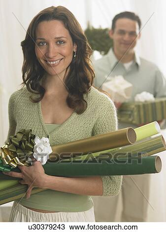 Stock Image - Couple with Christmas gifts and wrapping paper. Fotosearch