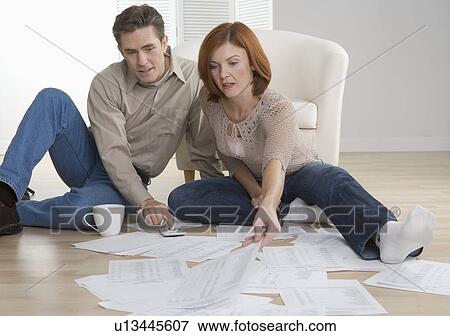 Couple with paperwork on floor View Large Photo Image Stock Photo - Couple with paperwork on floor. Fotosearch