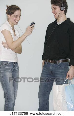 Stock Photograph - Couple with personal stereo and mobile phone. Fotosearch