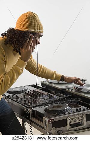 Stock Image - DJ working at music mixing board. Fotosearch
