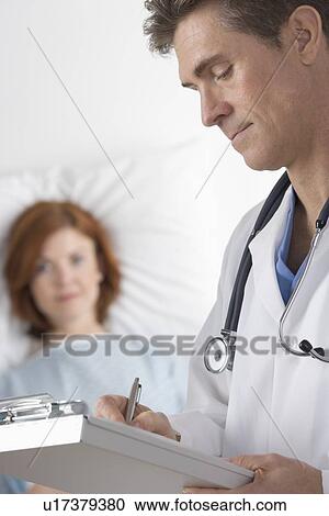 Stock Image - Doctor taking notes with patient. Fotosearch
