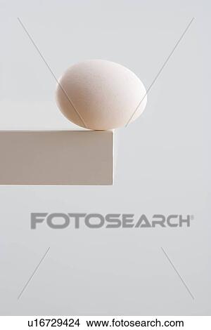 Picture - Egg on edge of table. Fotosearch