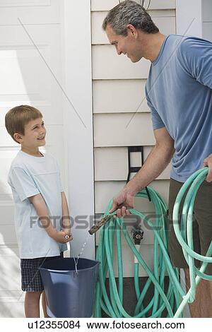 Father and young son filling bucket with hose View Large Photo Image Picture - Father and young son filling bucket with hose. Fotosearch