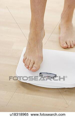 Stock Photography - Feet stepping onto bathroom scale. Fotosearch