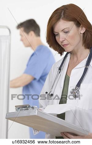 Stock Photograph - Female healthcare professional consulting chart. Fotosearch