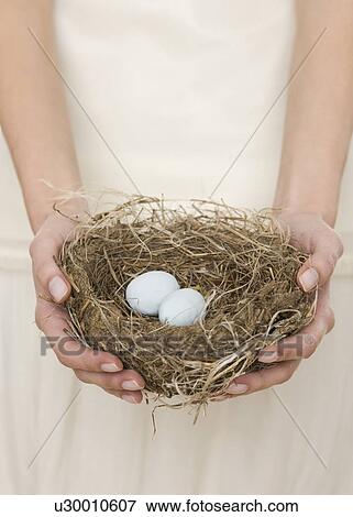 Stock Photo - Female holding nest with eggs. Fotosearch
