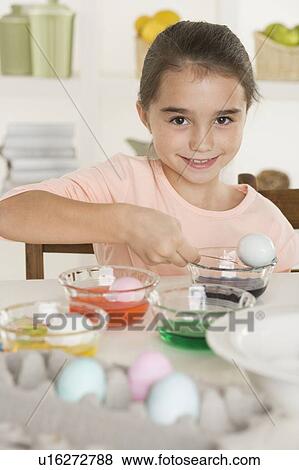 Stock Photo - Girl coloring Easter eggs. Fotosearch
