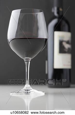 Stock Image - Glass of red wine with bottle. Fotosearch