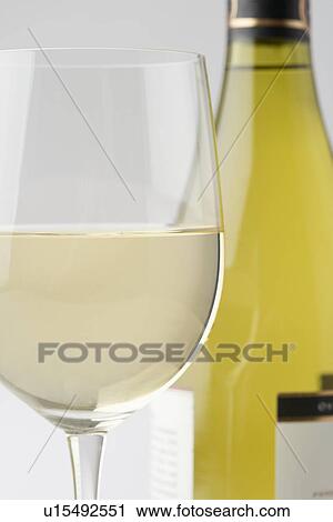 Stock Image - Glass of white wine with bottle. Fotosearch