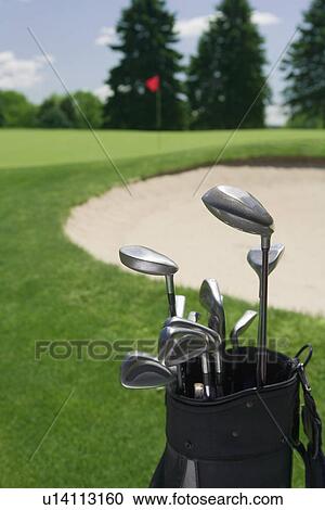 Stock Image - Golf clubs with course and sand trap in distance. Fotosearch