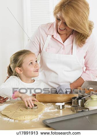 Stock Image - Grandmother and young granddaughter making cookies. Fotosearch