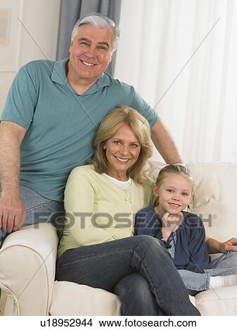 Grandparents and young granddaughter on sofa View Large Photo Image Picture - Grandparents and young granddaughter on sofa. Fotosearch