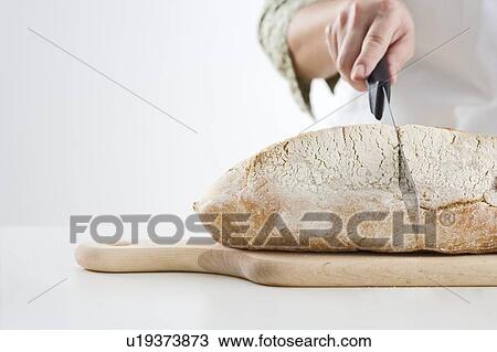Hand cutting loaf of bread View Large Photo Image Stock Image - Hand cutting loaf of bread. Fotosearch