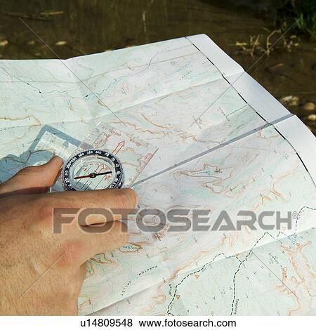 Stock Photo - Hand holding a compass and map. Fotosearch