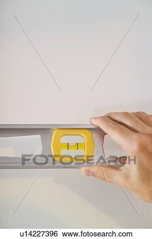 Hand holding a level against a wall View Large Photo Image Stock Photograph - Hand holding a level against a wall. Fotosearch