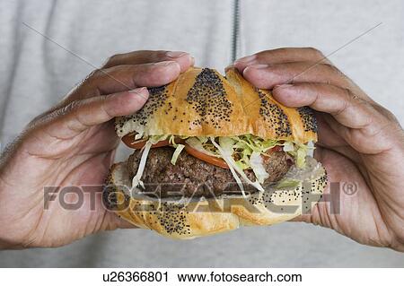 Stock Image - Hands holding hamburger. Fotosearch