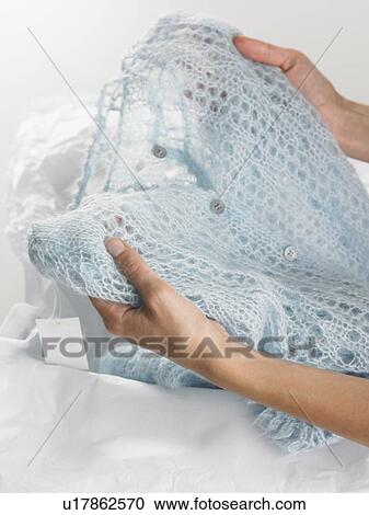 Stock Image - Hands holding new sweater. Fotosearch