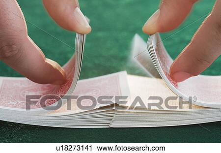 Stock Image - Hands shuffling cards on poker table. Fotosearch