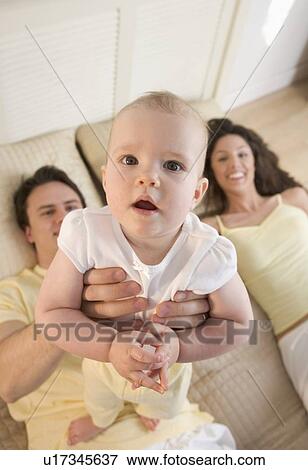 Infant held up by smiling couple View Large Photo Image Stock Photo - Infant held up by smiling couple. Fotosearch