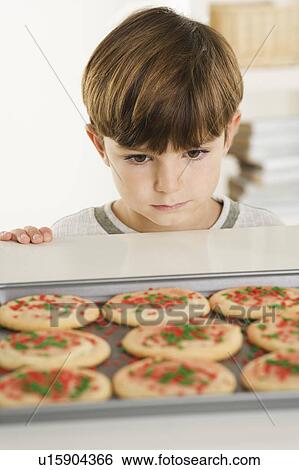 Stock Photograph - Little boy eyeing cookies. Fotosearch