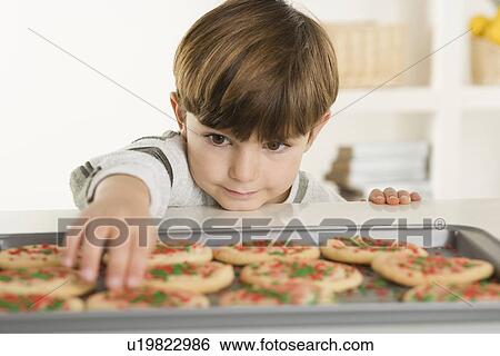 Stock Photograph - Little boy reaching for a cookies. Fotosearch