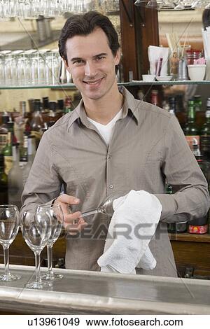 Stock Photo - Male bartender drying wine glasses. Fotosearch