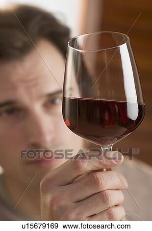 Man examining upheld glass of wine View Large Photo Image Stock Photo - Man examining upheld glass of wine. Fotosearch