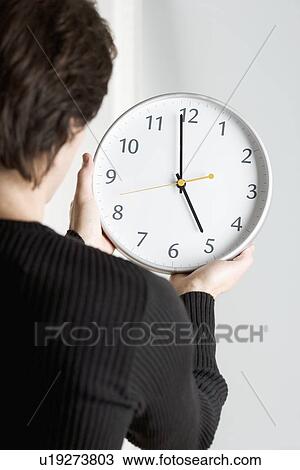 Stock Image - Man from behind holding clock. Fotosearch
