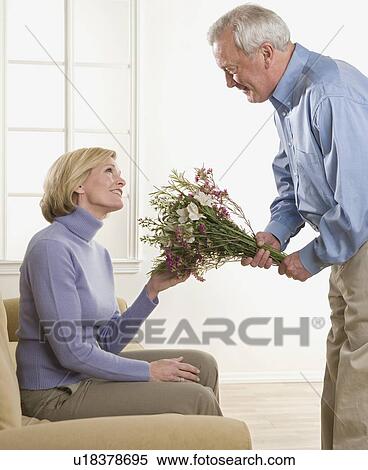 Stock Photography - Man giving flowers to his wife. Fotosearch