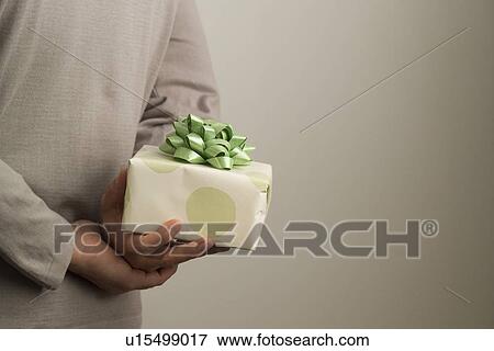 Stock Photo - Man hiding a gift behind his back. Fotosearch