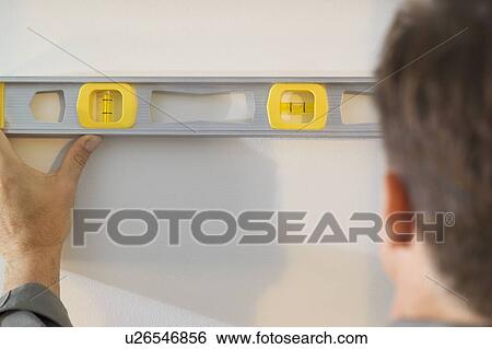 Man holding a level against a wall View Large Photo Image Stock Photograph - Man holding a level against a wall. Fotosearch