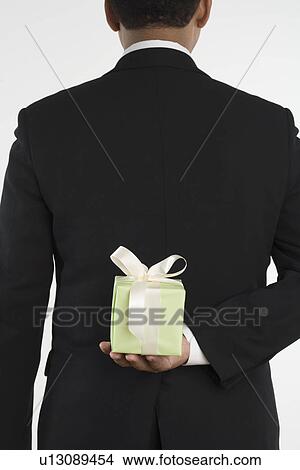 Picture - Man holding gift against his back. Fotosearch