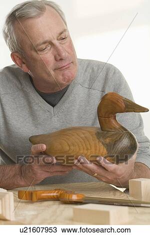 Stock Image - Man holding handmade wooden duck. Fotosearch