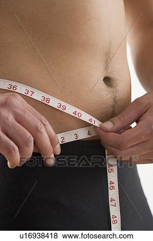 Man measuring his waist View Large Photo Image Stock Photo - Man measuring his waist. Fotosearch