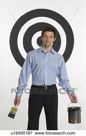 Stock Photo - Man painting bull’s eye on wall. Fotosearch