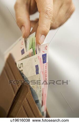 Stock Photo - Man removing Euro bills from his wallet. Fotosearch